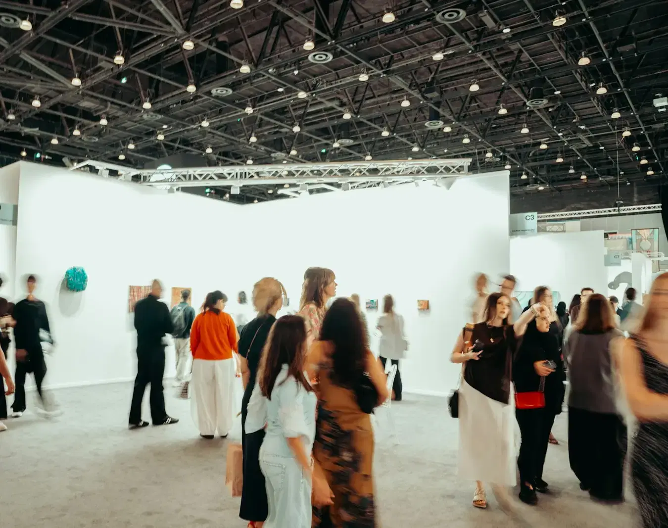 Visitors walking between white walls in a large, bright exhibition hall