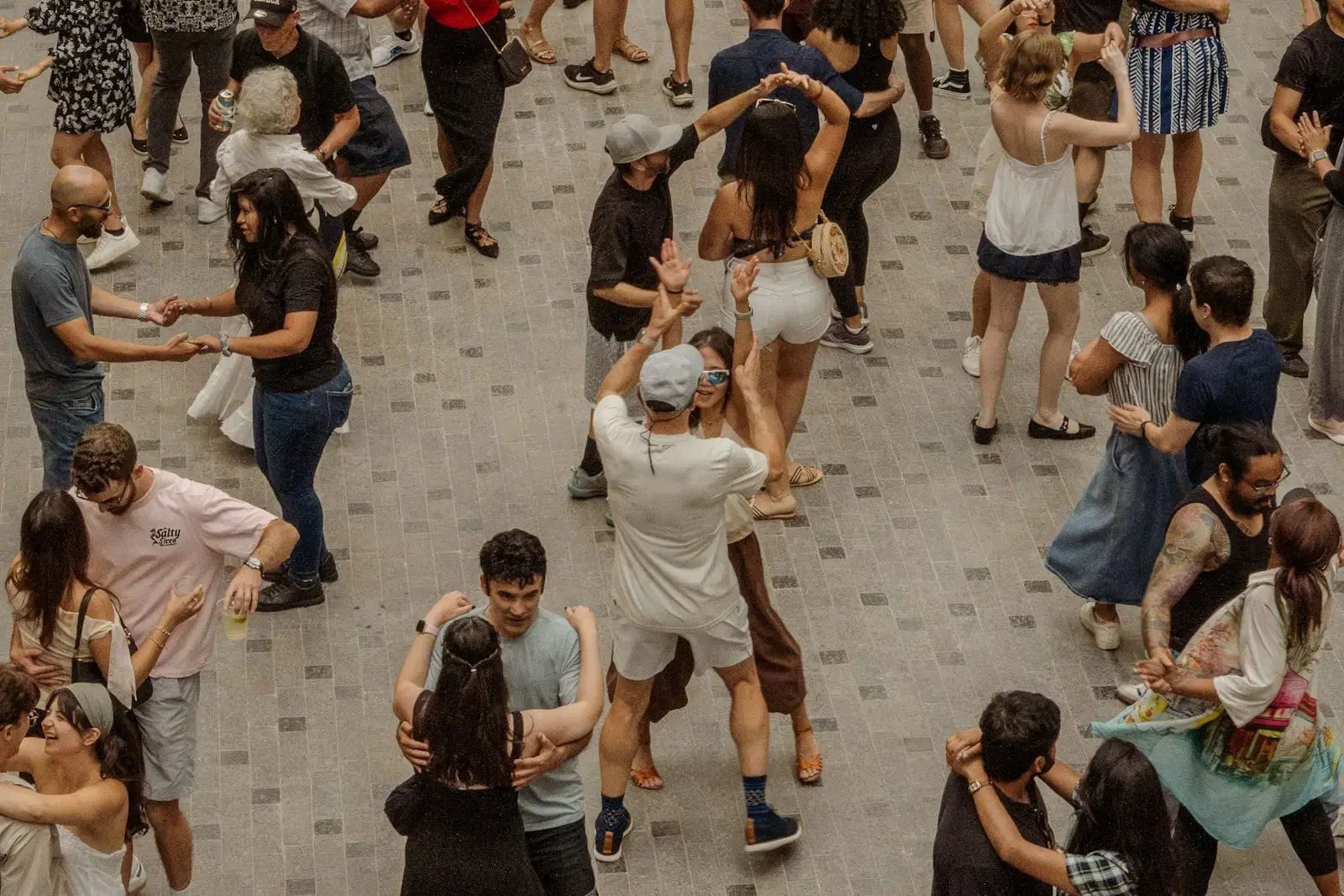 Couples dancing together on the paving of a public square, seen from above