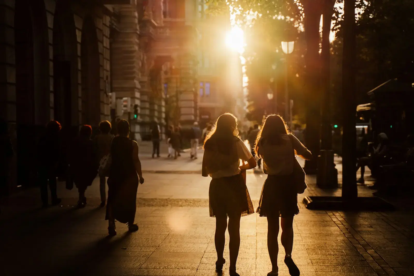 Two people walking down a city street toward the setting sun